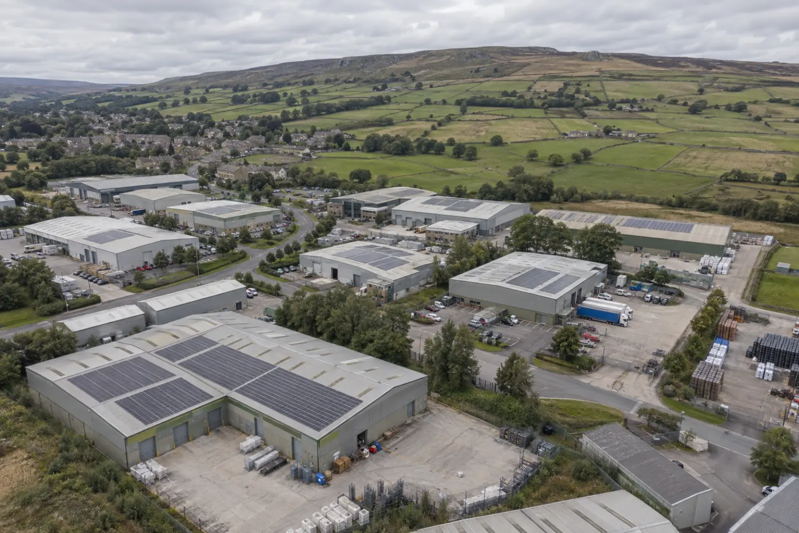 West Yorkshire industrial park below moorland, with solar on several roofs