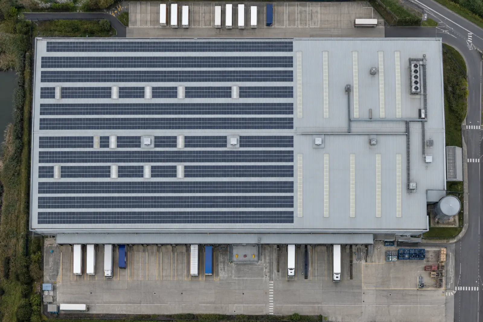 Straight down view of a distribution warehouse roof, about two thirds covered with panels and the rest bare cladding and rooflights