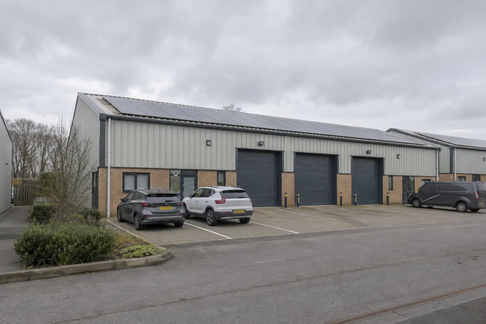 A light industrial unit with a small rooftop array above roller shutter doors